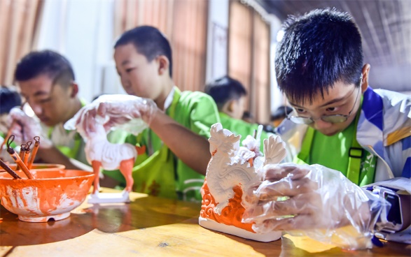 小朋友们在洛阳市孟津区朝阳镇南石山村体验唐三彩素胎施釉技艺。图片来源:视觉中国